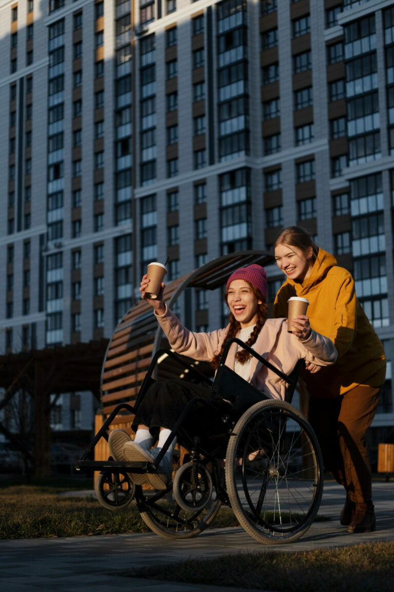 une femme pousse en pousse une autre en fauteuil roulant et rigolent ensemble